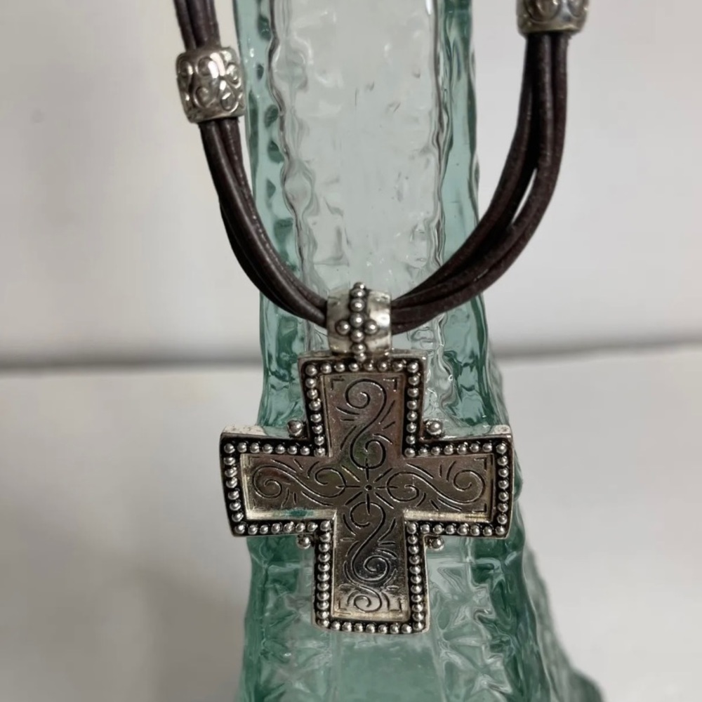 Silver cross pendant on a brown leather necklace/choker.